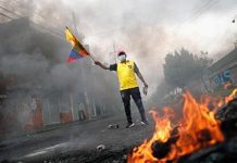 Un hombre sujetando una bandera de Ecuador protestando contra las políticas económicas del Gobierno de Guillermo Lasso en una calle de Quito. REUTERS/ADRIANO MACHADO
