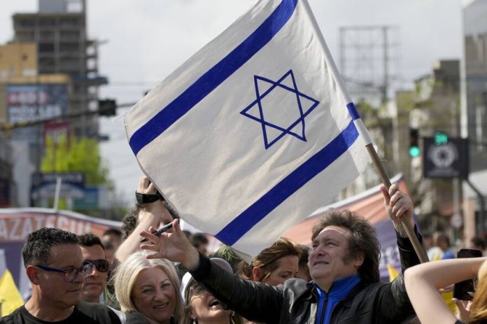 Javier Milei, de la Libertad Avanza, sostiene una bandera israelí durante su caravana por Lomas de Zamora, el lunes 16 de octubre de 2023 Natacha Pisarenko - AP